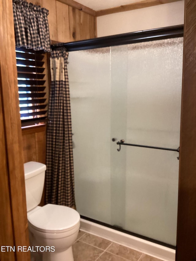 bathroom featuring tile patterned flooring, wood walls, toilet, and curtained shower