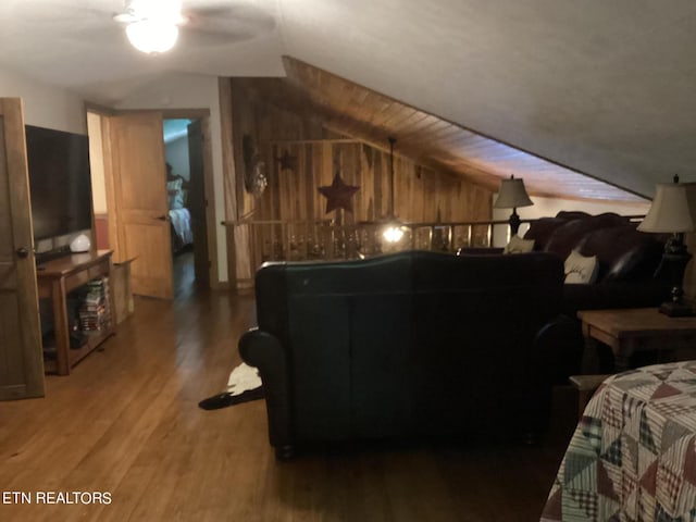 living room featuring lofted ceiling, ceiling fan, wood walls, and hardwood / wood-style flooring