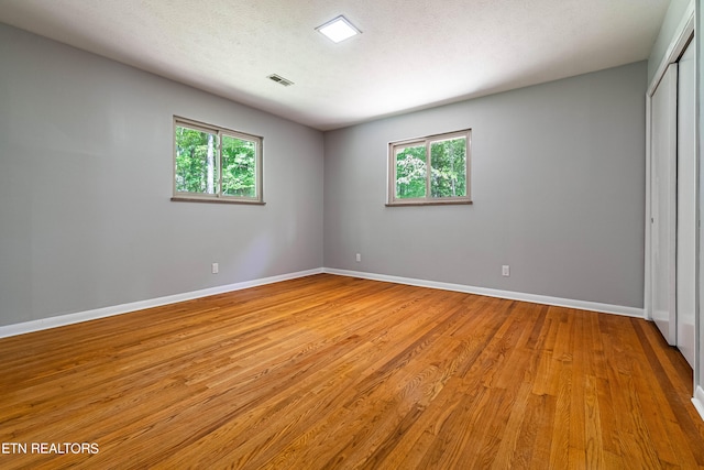 empty room with a textured ceiling and light hardwood / wood-style flooring