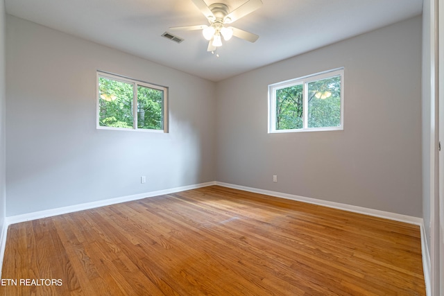 spare room featuring light hardwood / wood-style floors, ceiling fan, and a wealth of natural light