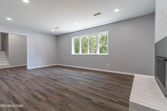 unfurnished living room with a textured ceiling and dark hardwood / wood-style flooring