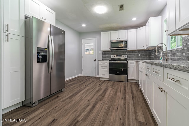 kitchen with appliances with stainless steel finishes, dark hardwood / wood-style floors, light stone counters, and white cabinets