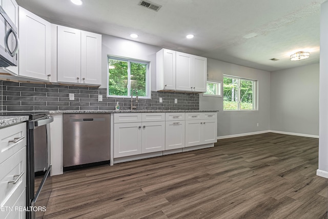 kitchen with light stone counters, white cabinets, tasteful backsplash, dark wood-type flooring, and appliances with stainless steel finishes