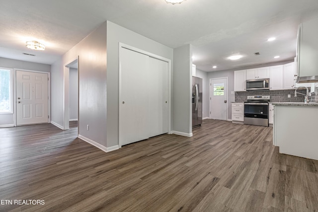 kitchen featuring appliances with stainless steel finishes, plenty of natural light, dark hardwood / wood-style floors, and white cabinetry