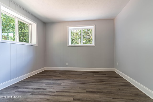 spare room with a textured ceiling, wooden walls, and dark hardwood / wood-style flooring