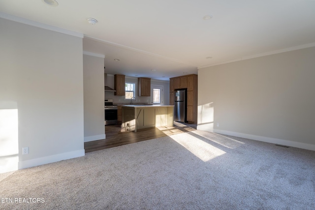 unfurnished living room featuring sink, crown molding, and carpet floors