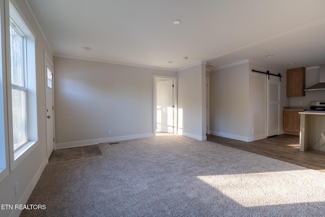 unfurnished room with crown molding, carpet floors, and a barn door