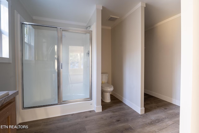 bathroom featuring a shower with shower door, crown molding, and toilet