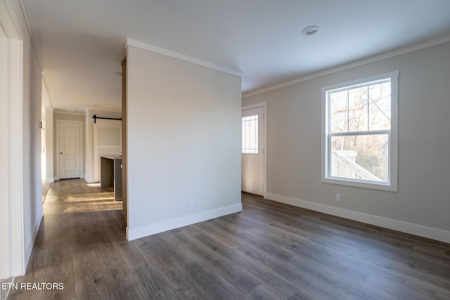 empty room featuring ornamental molding, dark hardwood / wood-style flooring, and a barn door