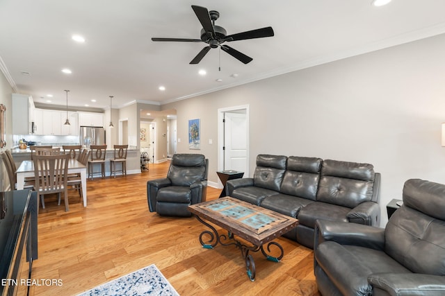 living room featuring ornamental molding, light hardwood / wood-style floors, and ceiling fan