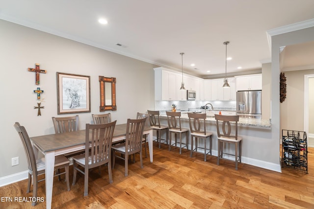 dining room with light wood-type flooring and ornamental molding