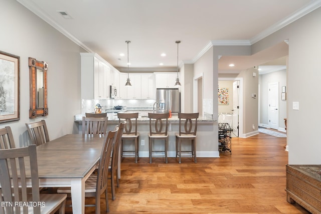 dining space featuring light hardwood / wood-style flooring and crown molding