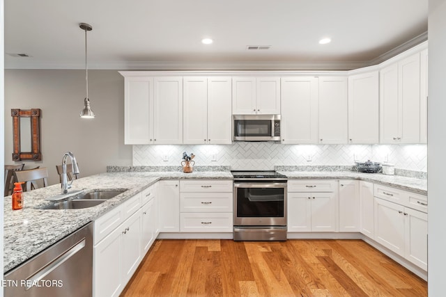 kitchen featuring pendant lighting, white cabinets, sink, light hardwood / wood-style flooring, and appliances with stainless steel finishes