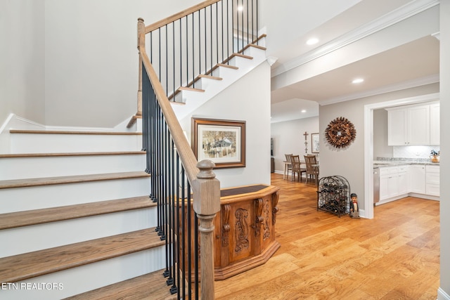 stairs featuring ornamental molding and hardwood / wood-style floors