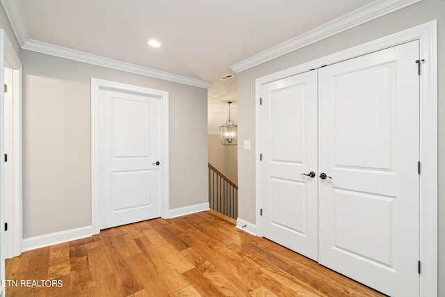 hallway with light wood-type flooring, crown molding, and a chandelier