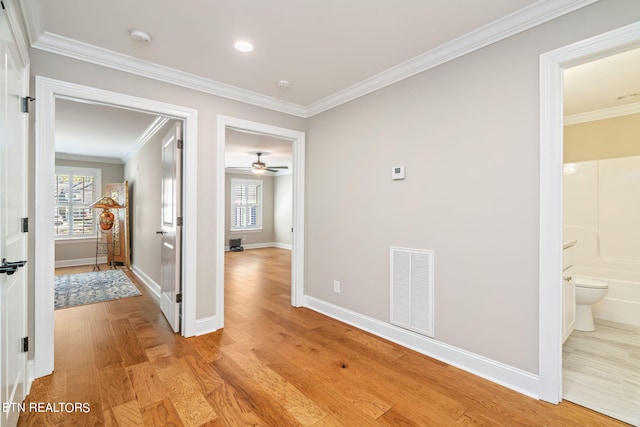 corridor featuring light wood-type flooring and ornamental molding