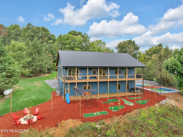 rear view of house with a balcony, a swimming pool, a lawn, and a patio area