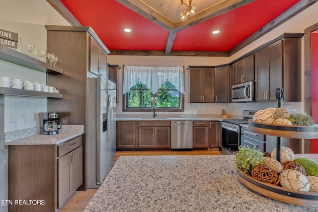 kitchen with appliances with stainless steel finishes, light wood-type flooring, light stone countertops, and sink