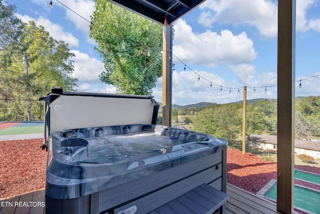 deck with a mountain view and a hot tub