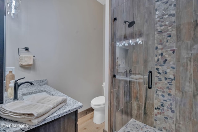 bathroom with hardwood / wood-style floors, an enclosed shower, vanity, and toilet