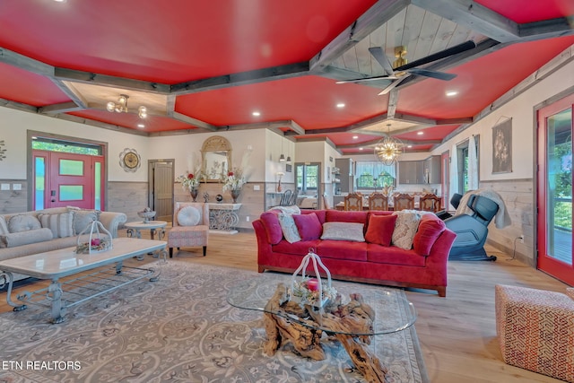 living room with ceiling fan with notable chandelier, beamed ceiling, and light wood-type flooring