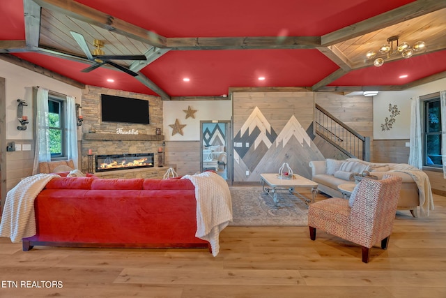 living room featuring wood-type flooring, wooden walls, a fireplace, and ceiling fan