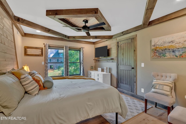 bedroom with light wood finished floors and beamed ceiling