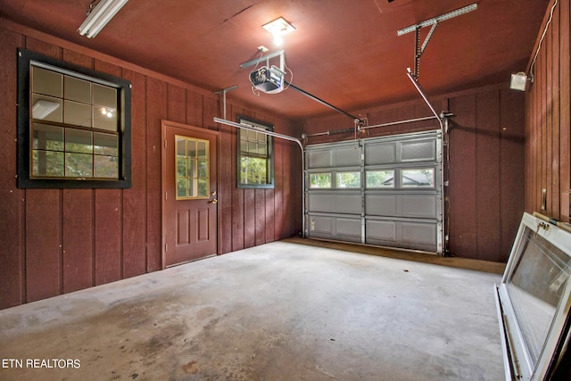 garage with a garage door opener and wood walls