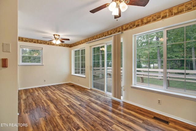 unfurnished room with plenty of natural light, dark hardwood / wood-style floors, and ceiling fan