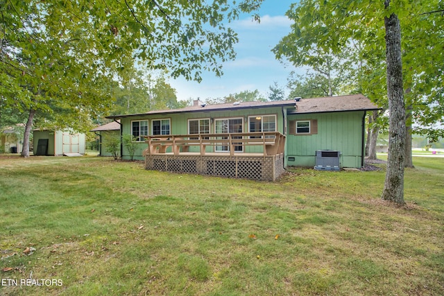 rear view of property featuring a shed, a yard, a wooden deck, and central AC unit