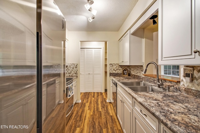 kitchen with tasteful backsplash, dark wood-type flooring, sink, appliances with stainless steel finishes, and a textured ceiling