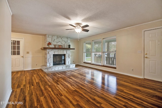 unfurnished living room featuring ceiling fan, a stone fireplace, a textured ceiling, dark hardwood / wood-style floors, and crown molding