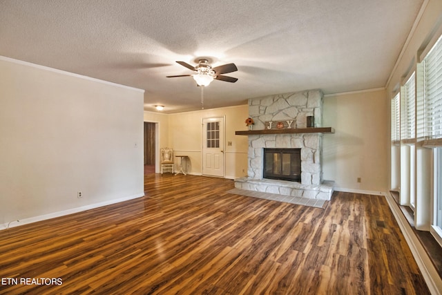 unfurnished living room featuring ceiling fan, dark hardwood / wood-style floors, a fireplace, crown molding, and a textured ceiling