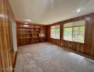 spare room featuring carpet floors and wood walls