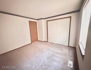 unfurnished bedroom featuring crown molding, a closet, and light colored carpet