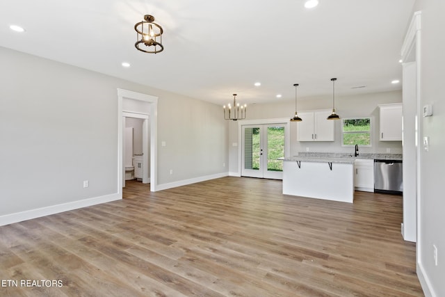 kitchen featuring a kitchen island, light hardwood / wood-style flooring, pendant lighting, stainless steel dishwasher, and white cabinetry