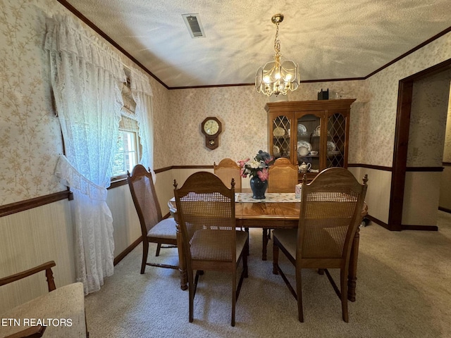 dining room with ornamental molding, a textured ceiling, carpet floors, and an inviting chandelier