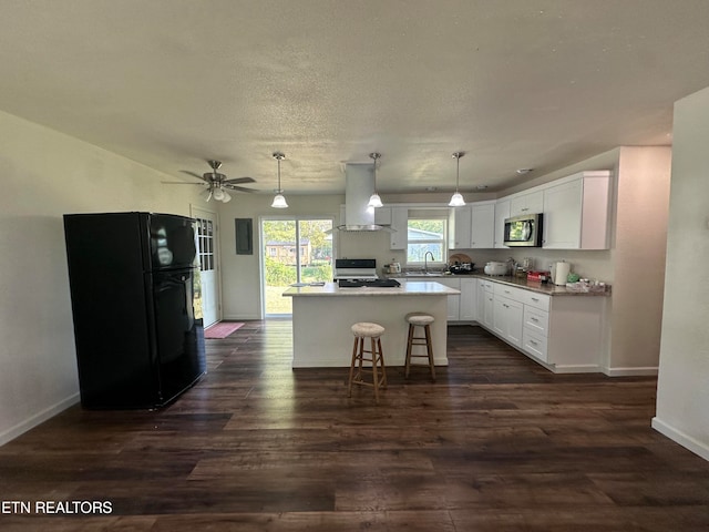 kitchen featuring white cabinets, black refrigerator, ventilation hood, gas range, and a center island