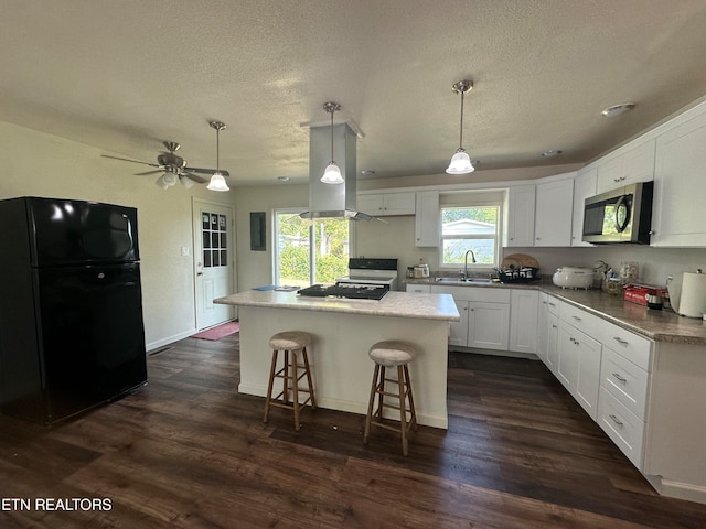 kitchen with black fridge, dark wood-type flooring, white cabinets, a kitchen island, and decorative light fixtures