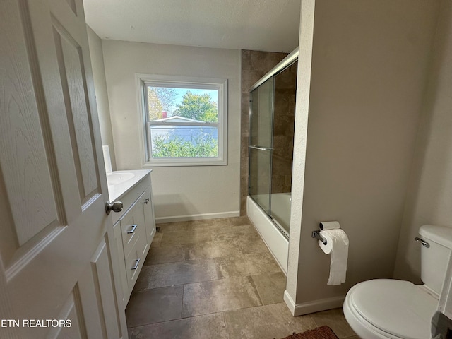 full bathroom featuring enclosed tub / shower combo, vanity, toilet, and a textured ceiling