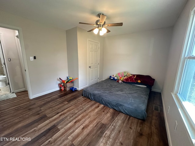 bedroom featuring dark hardwood / wood-style floors, ceiling fan, and ensuite bath