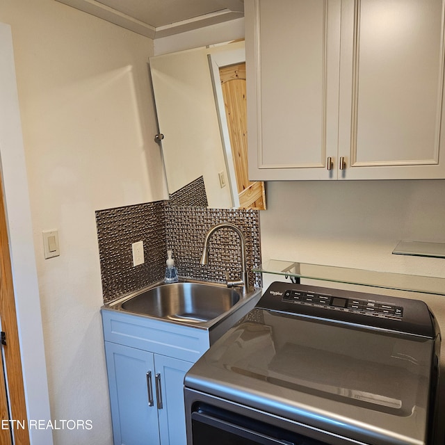 kitchen featuring white cabinetry, sink, washer / dryer, and tasteful backsplash