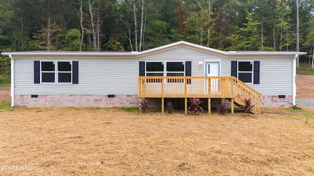 rear view of house featuring a wooden deck and a lawn