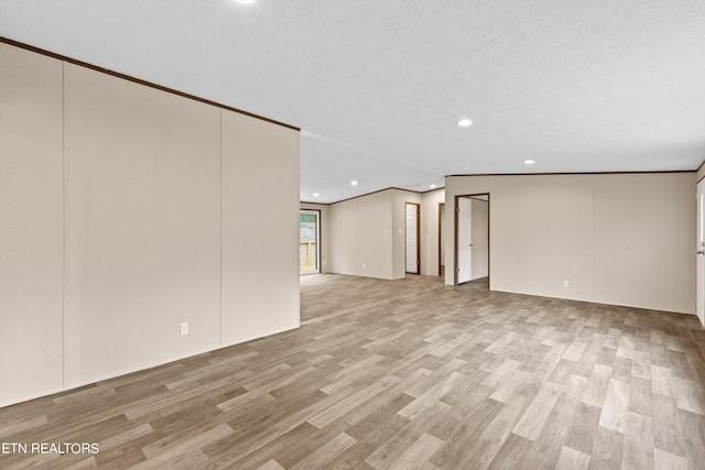 spare room featuring a textured ceiling, light hardwood / wood-style flooring, and ornamental molding