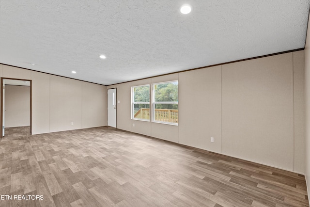 unfurnished room featuring ornamental molding, light wood-type flooring, and a textured ceiling