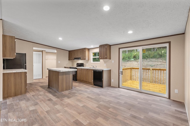 kitchen with ornamental molding, a textured ceiling, black appliances, a center island, and light hardwood / wood-style floors