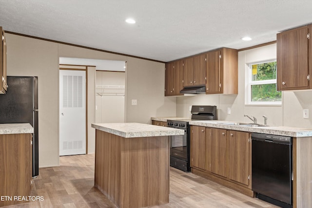 kitchen with a textured ceiling, a center island, light hardwood / wood-style flooring, black appliances, and ornamental molding