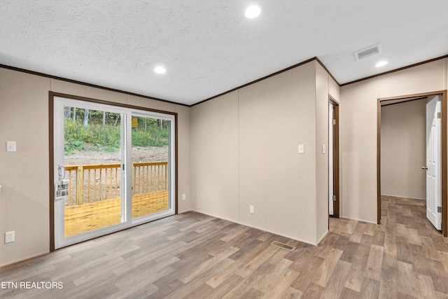 empty room with ornamental molding, light wood-type flooring, and a textured ceiling