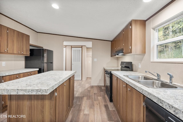 kitchen featuring sink, a kitchen island, wood-type flooring, black appliances, and crown molding