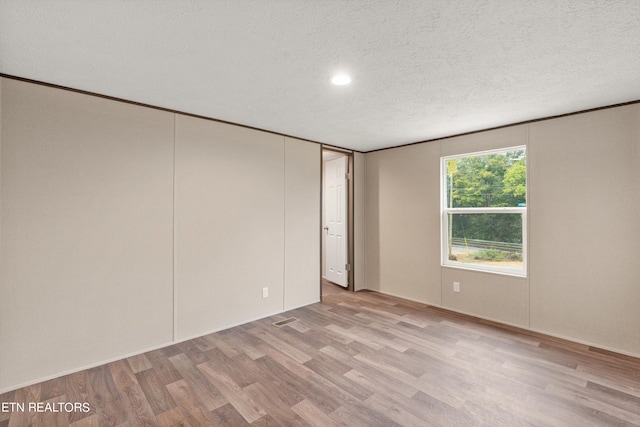 unfurnished room featuring a textured ceiling and light hardwood / wood-style flooring